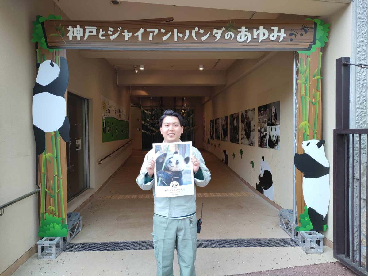 パンダ館の前で「ありがとうタンタン」のポスターを持つ王子動物園広報